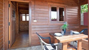A wooden cabin with a dining area featuring a table, chairs, and a potted plant. - Holiday Home "Casa Juana Madera" with Shared Pool and Air Conditioning (Zahora)