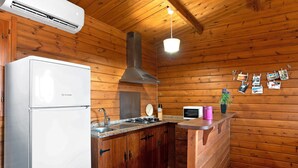 A wooden cabin interior with a kitchen area, including a refrigerator, stove, microwave, and wooden cabinets. - Holiday Home "Casa Juana Madera" with Shared Pool and Air Conditioning (Zahora)