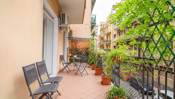 A balcony with chairs, potted plants, and a view of neighboring buildings. - Holiday Apartment "Violet House" with Private Terrace, Air Conditioning and Wi-Fi (Catania)