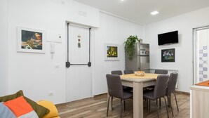A dining area with a table, chairs, a refrigerator, and a TV. - Holiday Apartment "Violet House" with Private Terrace, Air Conditioning and Wi-Fi (Catania)