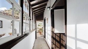 A narrow hallway with a wooden ceiling, potted plants, and a view of a hillside. - Vacation Home "Casa Rural El Palmar" with Mountain View, Private Terrace & Wi-Fi (Vallehermoso)