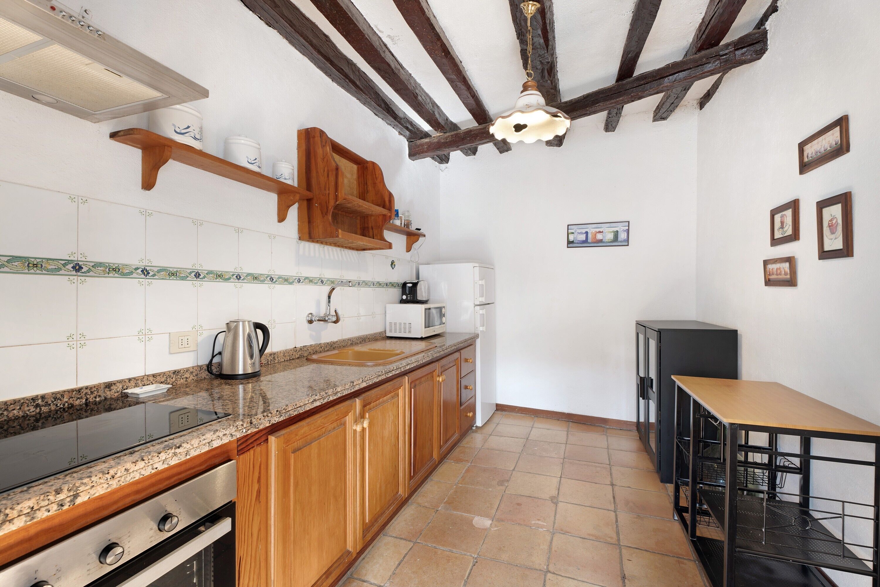 Una cocina con gabinetes de madera, encimera de granito, estufa, microondas y fregadero.