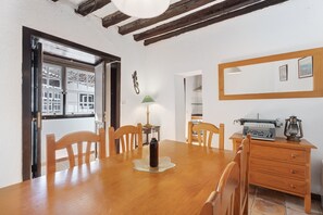 A dining area with a wooden table, chairs, a bottle, a typewriter, and a lamp. - Vacation Home "Casa Rural El Palmar" with Mountain View, Private Terrace & Wi-Fi (Vallehermoso)