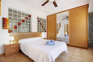 Una camera d'albergo con un letto grande, un armadio in legno, uno specchio e una finestra con vetri decorativi.