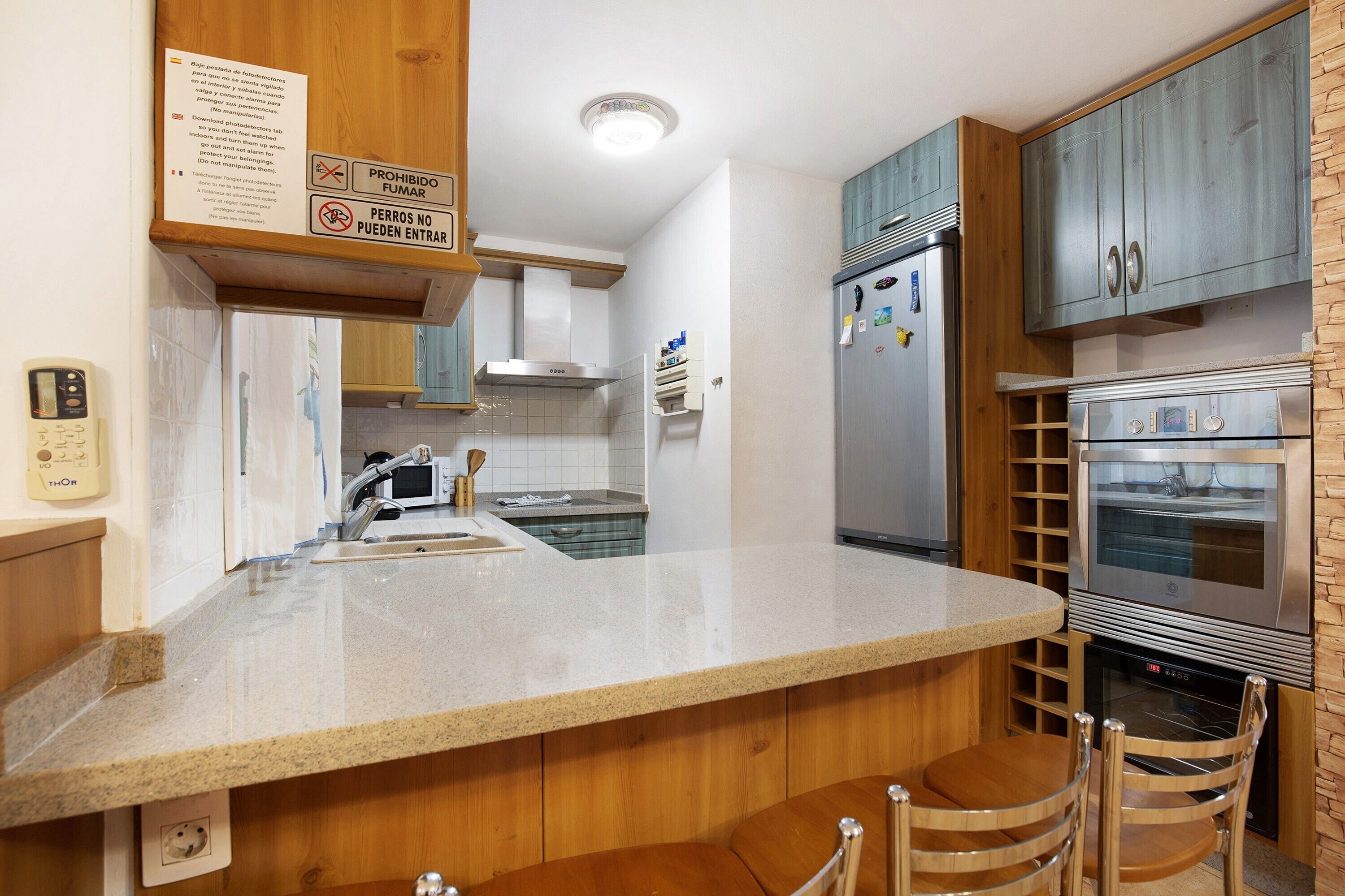Eine Küche mit Granit Arbeitsplatten, Edelstahlgeräten, Holzschränken und einem eingebauten Backofen.