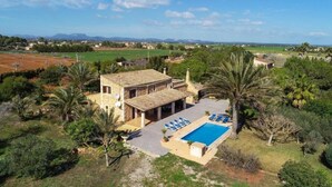 Eine Villa mit Schwimmbad, umgeben von Grün und Blick auf weit entfernte Felder.