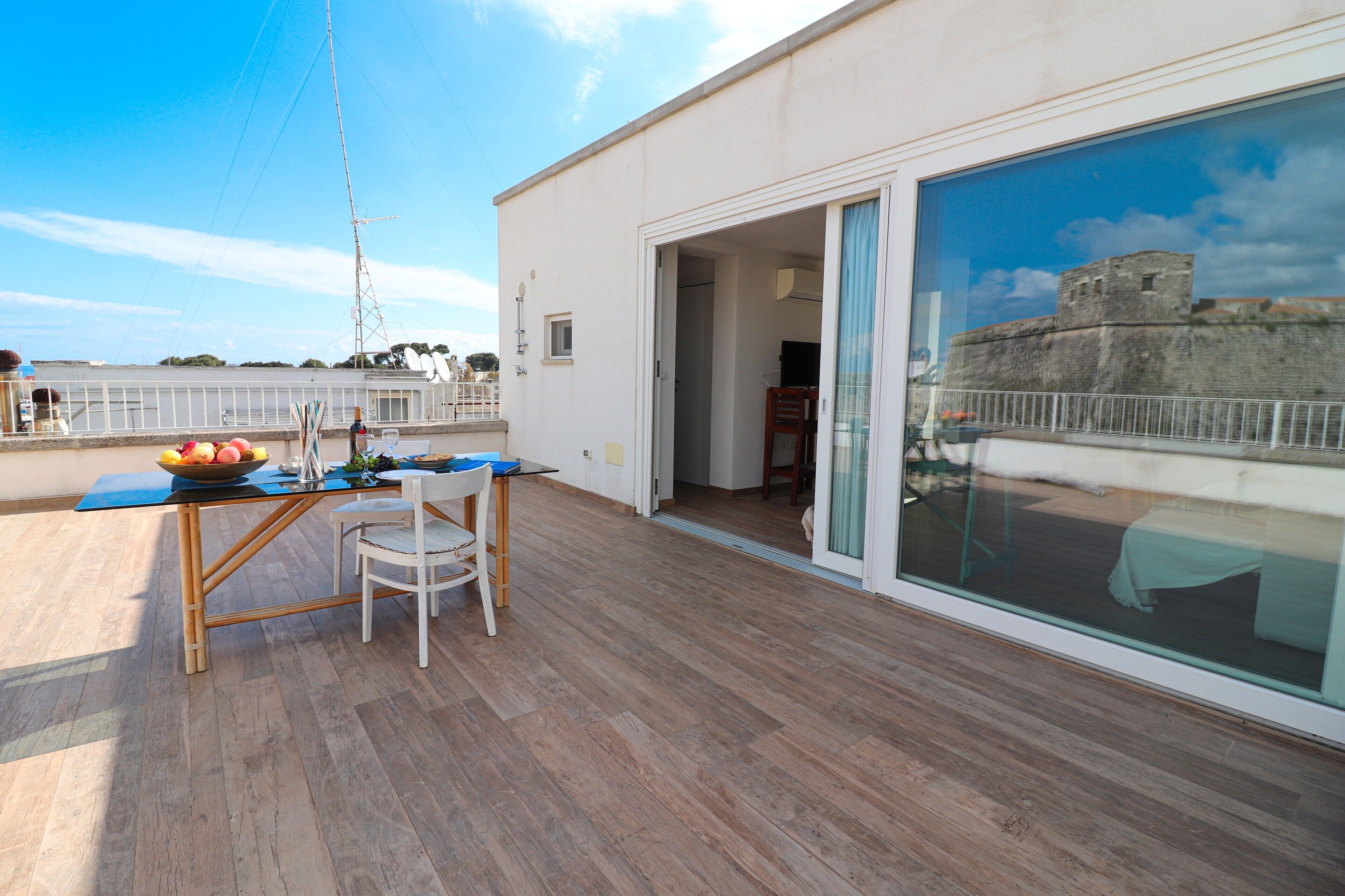 Un balcon avec une table, des chaises et un saladier rempli de fruits.