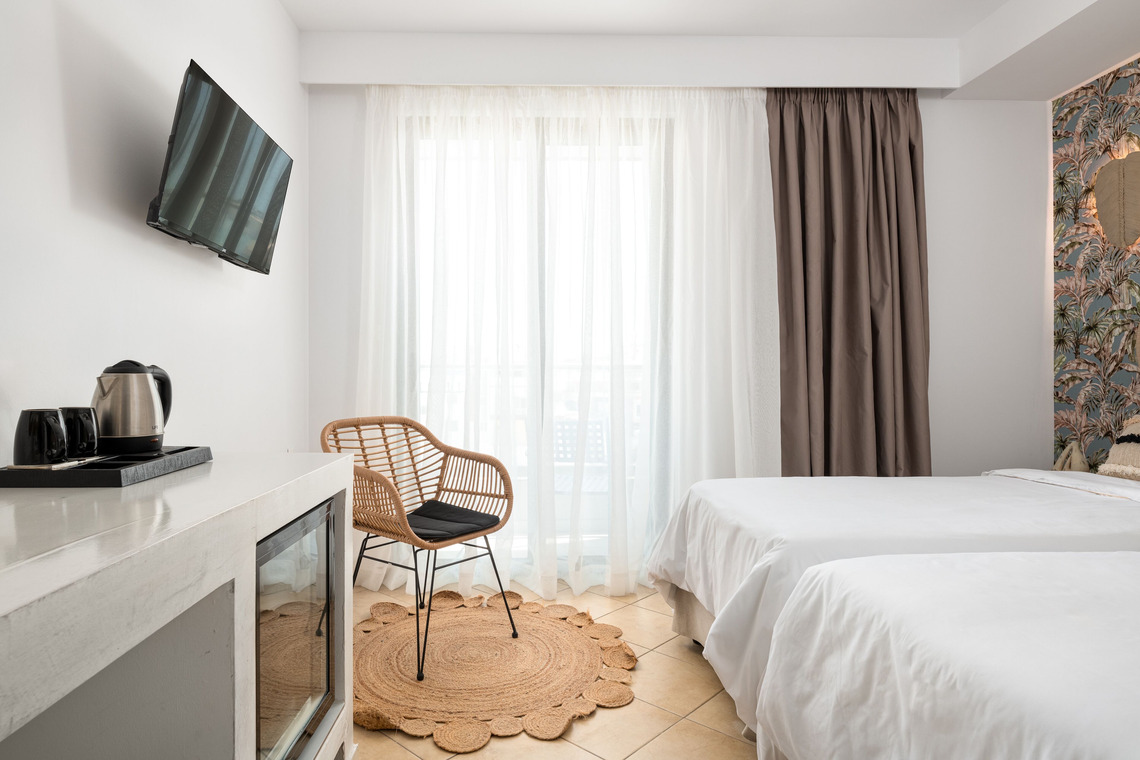 A hotel room with a bed, a chair, a TV, and a window with curtains.