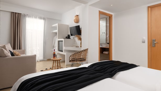 Ein modernes Hotelzimmer mit Bett, Sofa, Schreibtisch und Stuhl.