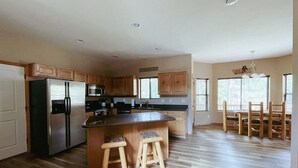 Een ruime keuken met houten kastjes, een roestvrijstalen koelkast, een magnetron en een groot eiland met krukken.