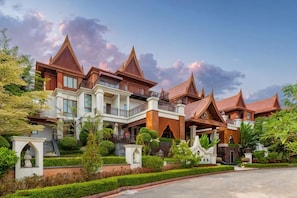 Un grand immeuble à étages, de style architectural traditionnel, doté de nombreux balcons et d’un jardin bien entretenu.
