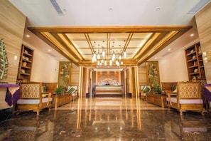 Un vestíbulo de hotel con una recepción, zona de estar y una pared decorativa.