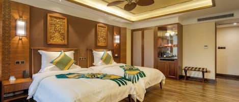 A hotel room with a large bed, two bedside tables, a ceiling fan, and a wooden floor.