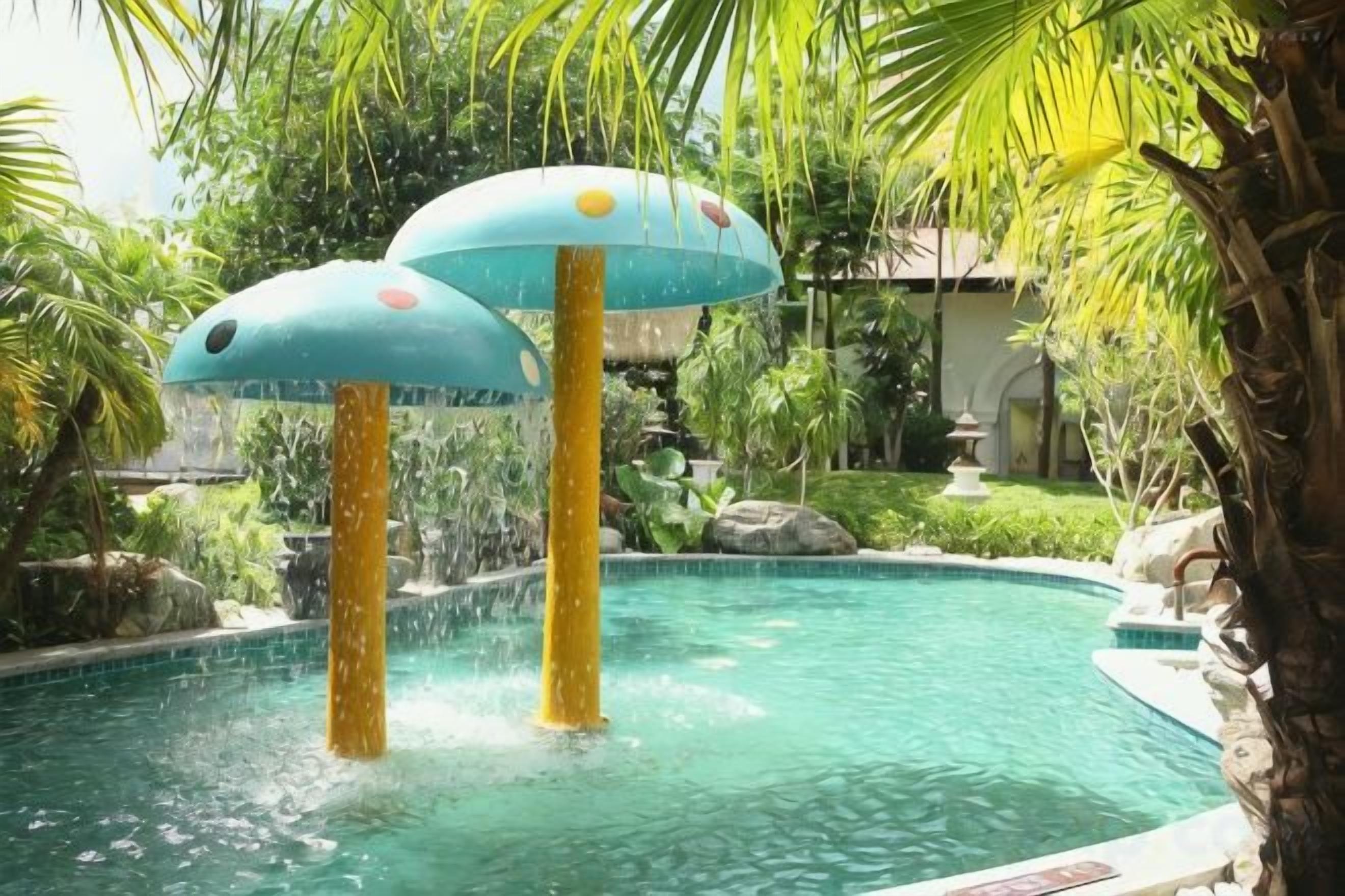 Ein Pool mit zwei Wasserspielen, umgeben von viel Grün.