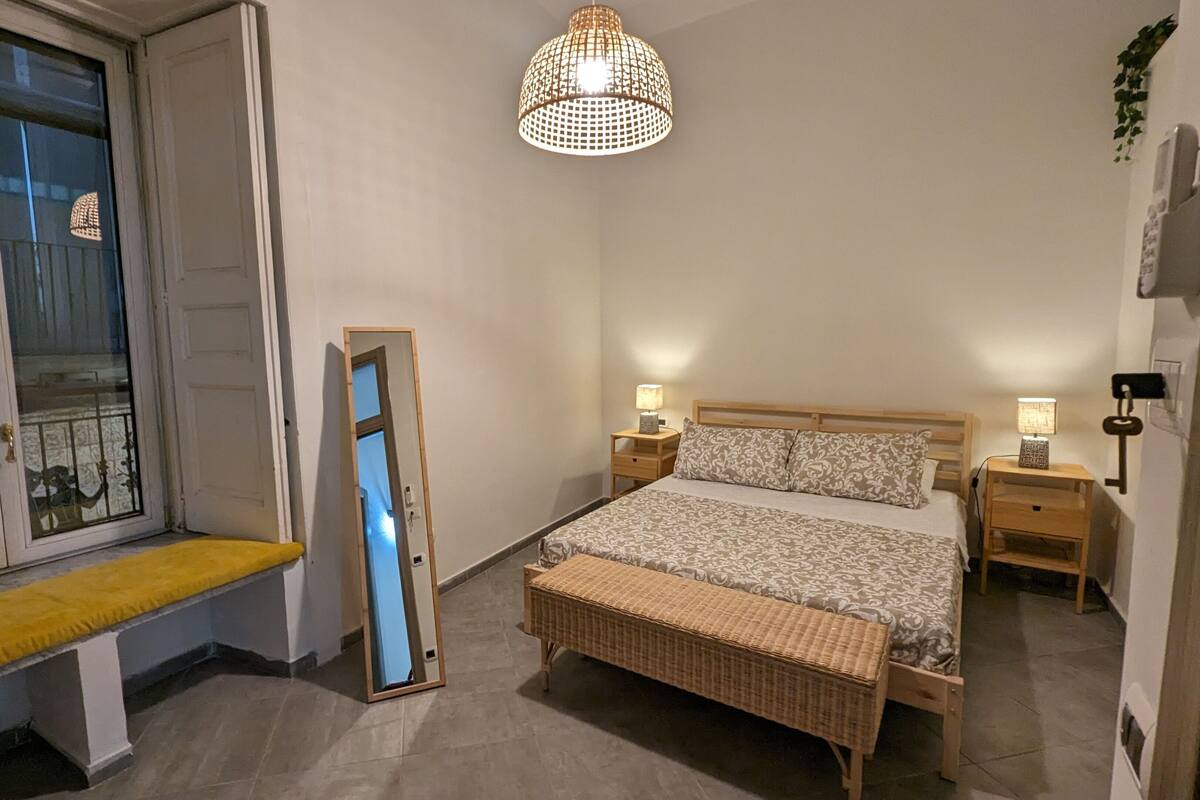 Ein Schlafzimmer mit einem Bett, Nachttischen, einer Bank, einer Hängeleuchte und einem Fenster mit Aussicht.