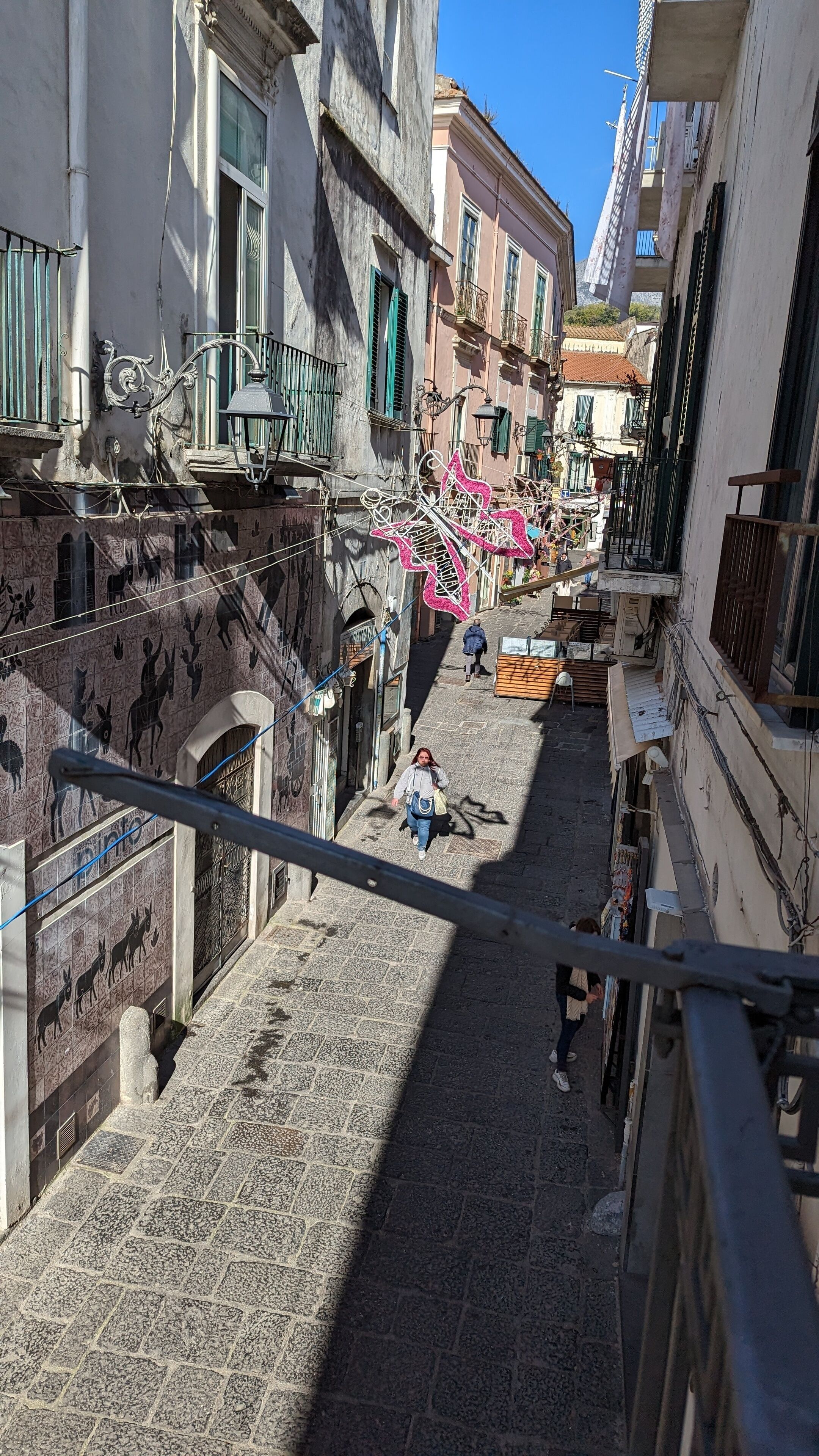 A narrow cobblestone street flanked by historic buildings with balconies and decorative ironwork.