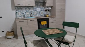 Una cocina compacta con zona de comedor, que incluye una mesa pequeña y dos sillas, un horno integrado y una ventana sobre el fregadero.