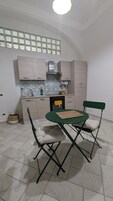 Una cocina compacta con zona de comedor, que incluye una mesa pequeña y dos sillas, un horno integrado y una ventana sobre el fregadero.