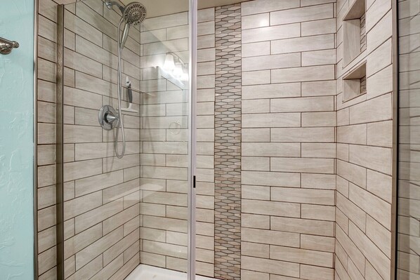 A shower area with tiled walls and a glass door.
