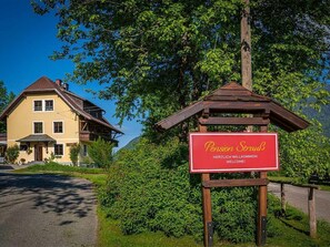 A yellow building with a red sign that reads "Pension Strub" and "Herzlich Willkommen!" - Appartement Gerlitzen - Pension Strauß (Rappitsch)