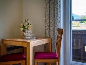 A wooden dining table with a vase of flowers and a glass. - Appartement Gerlitzen - Pension Strauß (Rappitsch)