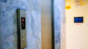 An elevator with a digital display and buttons, located in a hallway with marble walls. - Wanna Marine (Patong)