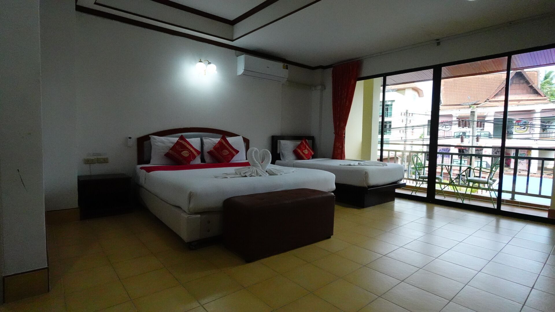 A hotel room with two beds, a large window, and a balcony.