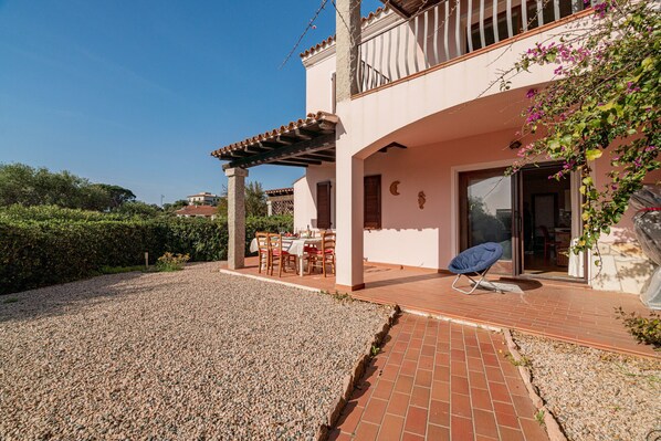 A two-story house with a patio, outdoor seating, and a covered area.