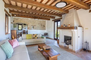 Ein Wohnzimmer mit einer Couch, Holzbalken, einem Kamin und einer Steinwand.
