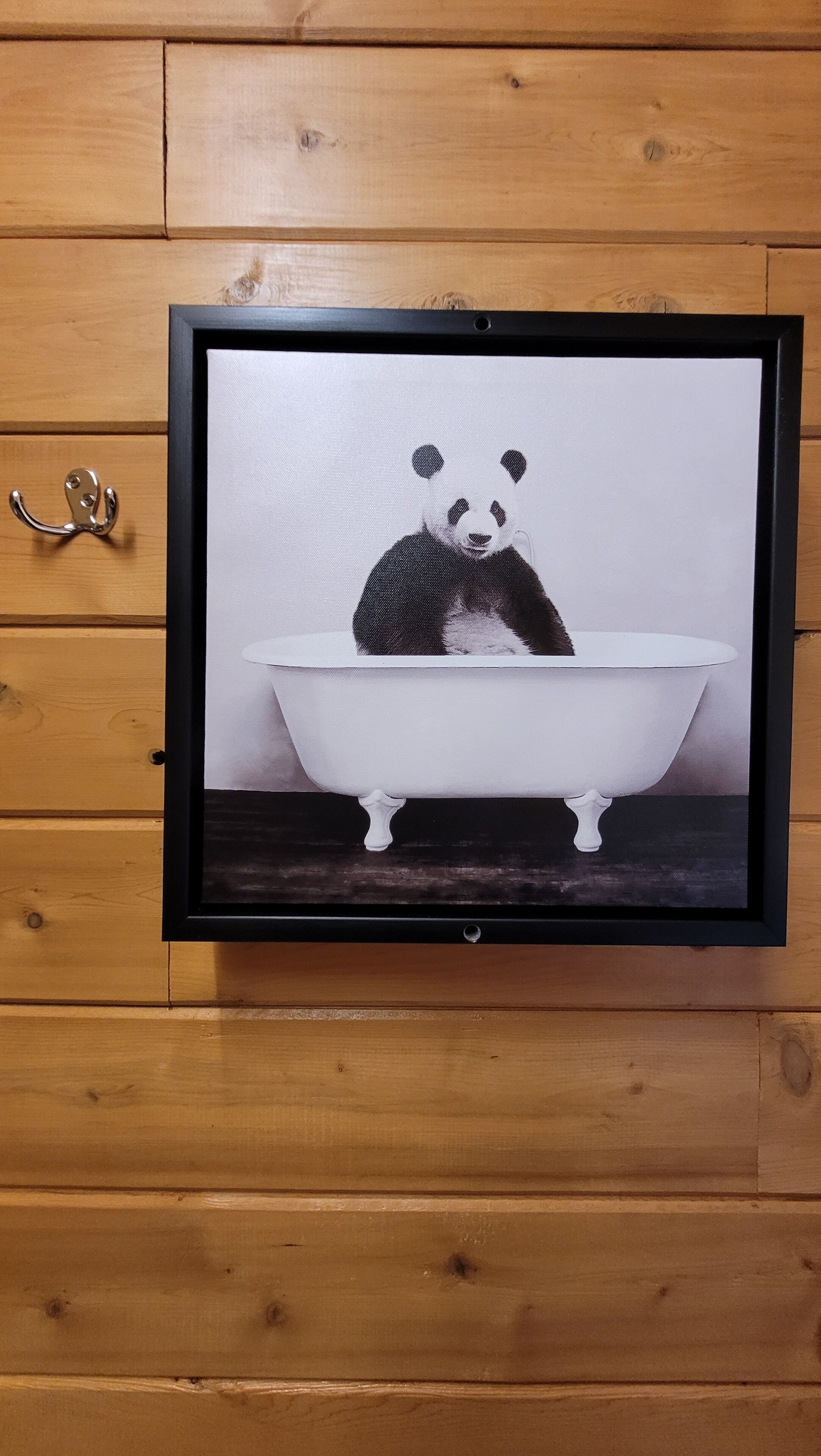 A framed artwork of a panda in a bathtub.