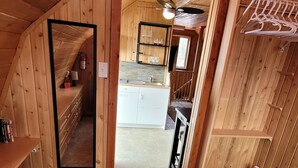 Une chambre confortable située dans les combles, avec des murs en bois, un lit, un miroir et une petite kitchenette.