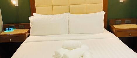 Una habitación de hotel con una cama, dos mesitas de noche y un reloj de pared.
