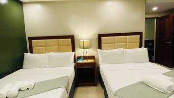 A hotel room with two beds, a nightstand with a lamp, and a digital clock.
