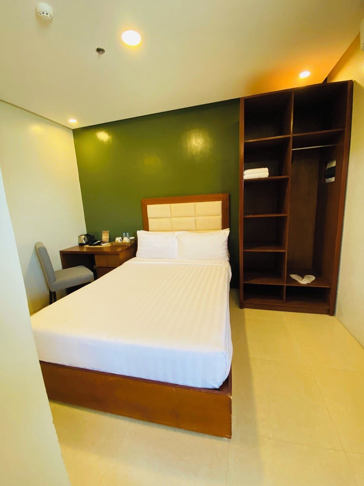 A hotel room with a bed, a desk, a chair, and a wardrobe.