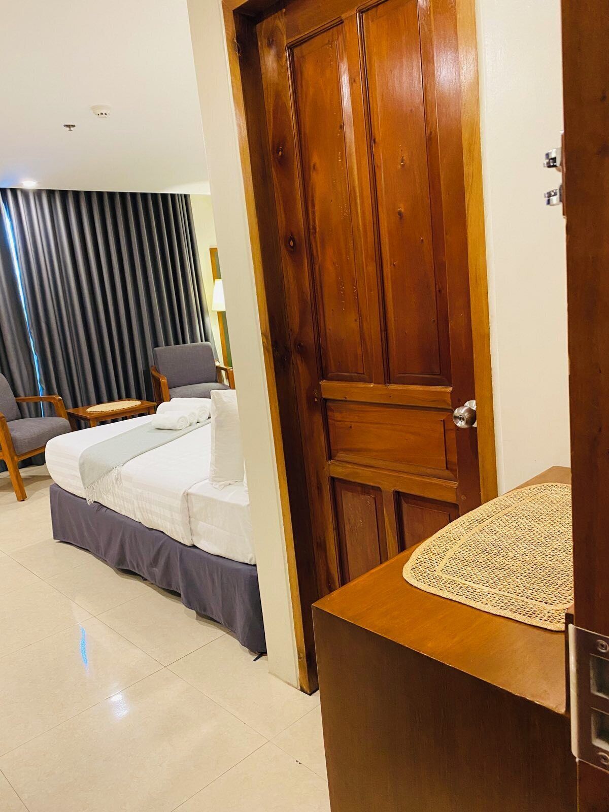 Ein Hotelzimmer mit Bett, Stuhl, Schreibtisch und Holztür.