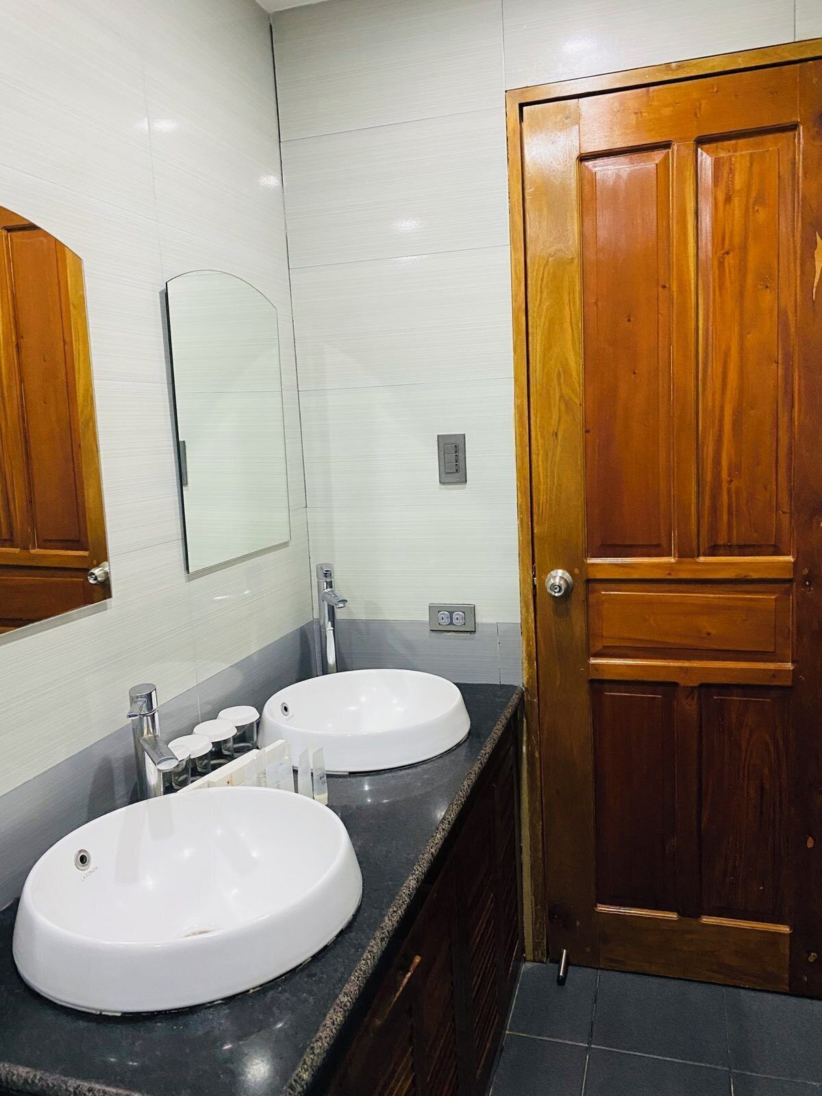 Un baño con dos lavamanos, un espejo y una puerta de madera.