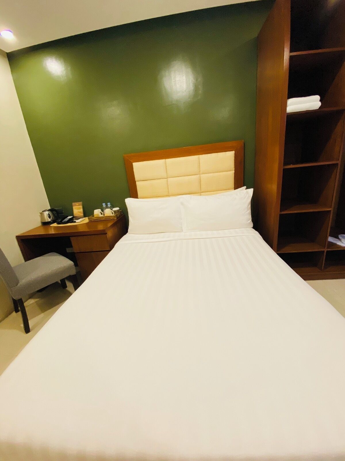 A hotel room with a bed, a desk, a chair, and a wardrobe.