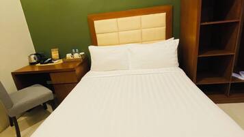 A hotel room with a bed, a desk, a chair, and a wardrobe.