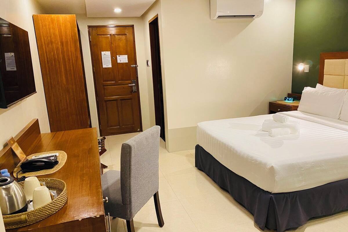 Une chambre d’hôtel équipée d’un lit, d’un bureau avec une chaise, d’une télévision et d’un appareil de climatisation.