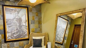 A room with a wicker chair, a large mirror, and a framed photograph on the wall. - Hotel Herencia 625 (Daraga)