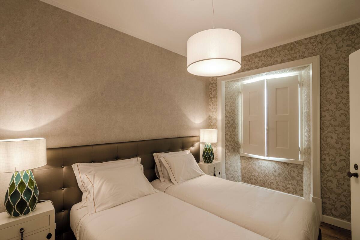 A bedroom with a large bed, a nightstand, a lamp, and a door.