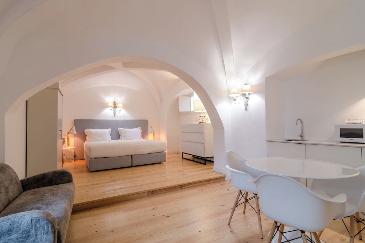 Un dormitorio moderno con cama, lámparas de noche, un escritorio y una silla.