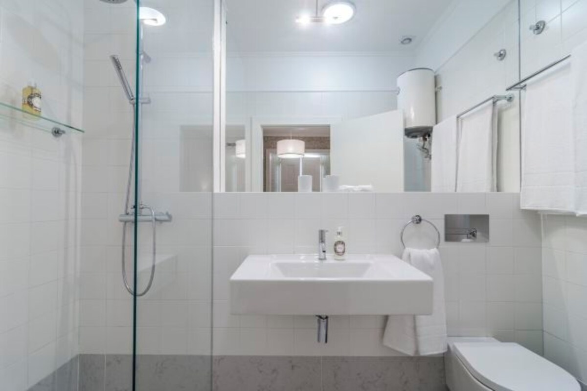 Un baño moderno con cabina de ducha de vidrio, lavamanos blanco y retrete.