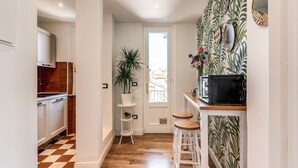 A narrow hallway with a checkered floor, a white door, and a kitchen area with a microwave and stools. - AwesHome - Pisa Park View Apartment (Pisa)