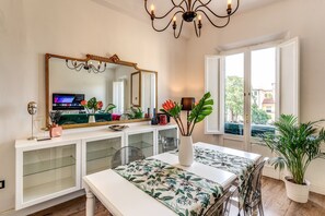 A modern dining area with a white table, a large mirror, and a potted plant. - AwesHome - Pisa Park View Apartment (Pisa)