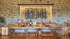 A dining area with a stone wall, a wine rack, and a wooden table set for four. - La Porcilaia, Pretaccione, Castelnuovo Berardenga, Siena and Chianti (Castelnuovo Berardenga)