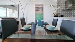 A dining area with a glass table, blue and white bowls, and modern pendant lights. - RDR299 - 2 Bedroom Frontline Puerto Banús BEST views (Marbella)