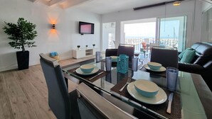 A modern dining area with a glass table, chairs, and a view of the city. - RDR299 - 2 Bedroom Frontline Puerto Banús BEST views (Marbella)