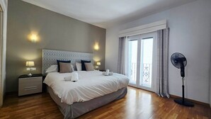 A hotel room with a large bed, bedside lamps, a standing fan, and a view of the outdoors through a window. - RDR299 - 2 Bedroom Frontline Puerto Banús BEST views (Marbella)