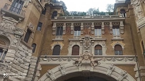 Une façade d’immeuble historique, ornée de détails architecturaux raffinés, notamment des statues et des moulures décoratives.